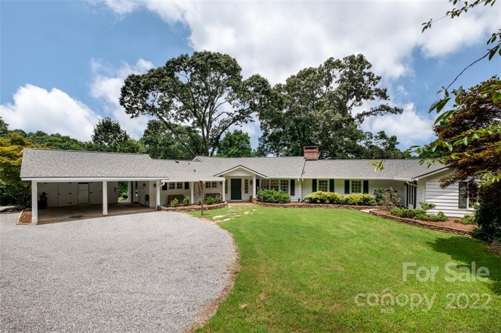 a view of a house with a big yard and large trees