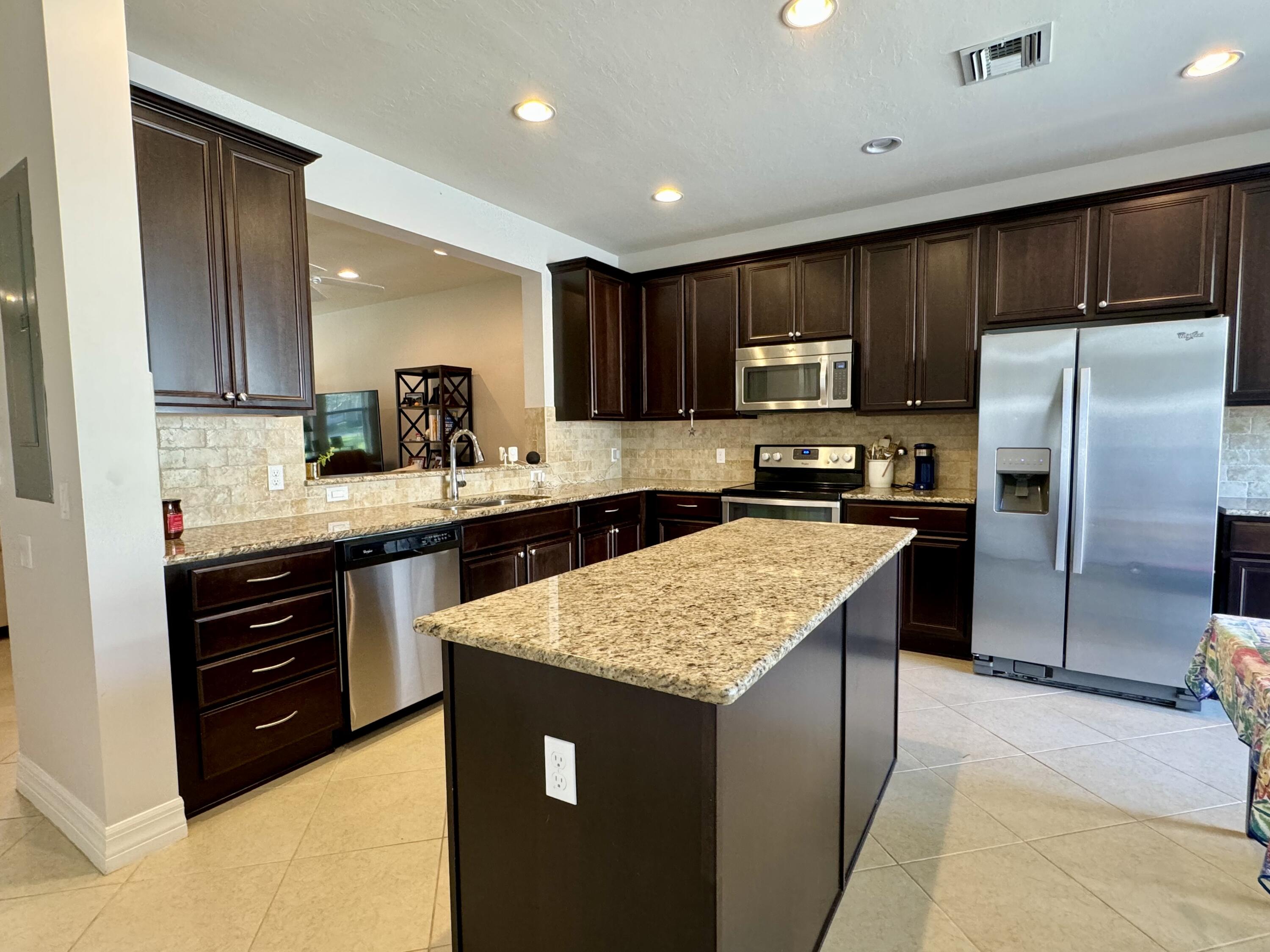 2758 Avalon Way Jupiter, FL 33458 - Photo 13 of 51 a kitchen with kitchen island granite countertop wooden cabinets a refrigerator and a sink