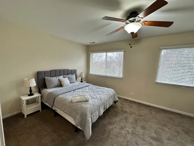 a bedroom with a bed ceiling fan and window