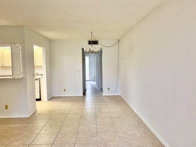55 Mansfield B, Unit 55 Boca Raton, FL 33434 - Photo 4 of 19 a view of a hallway with a dining space and chandelier