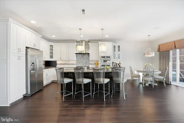 a kitchen with granite countertop a stove a sink dishwasher a dining table chairs and couches with wooden floor