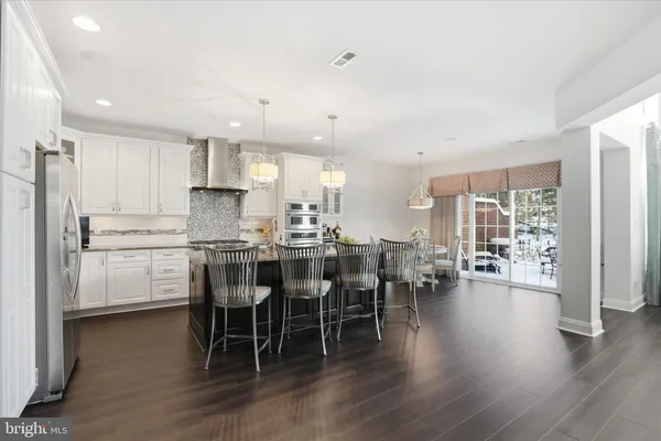 a kitchen with stainless steel appliances kitchen island granite countertop a dining table chairs and white cabinets