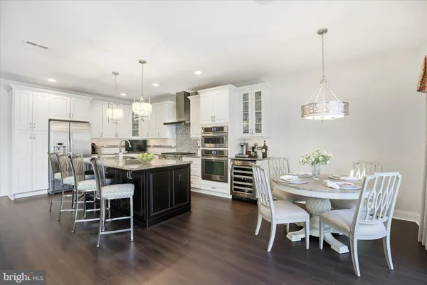 a kitchen with stainless steel appliances granite countertop a stove top oven a refrigerator a sink and a dining table with wooden floor