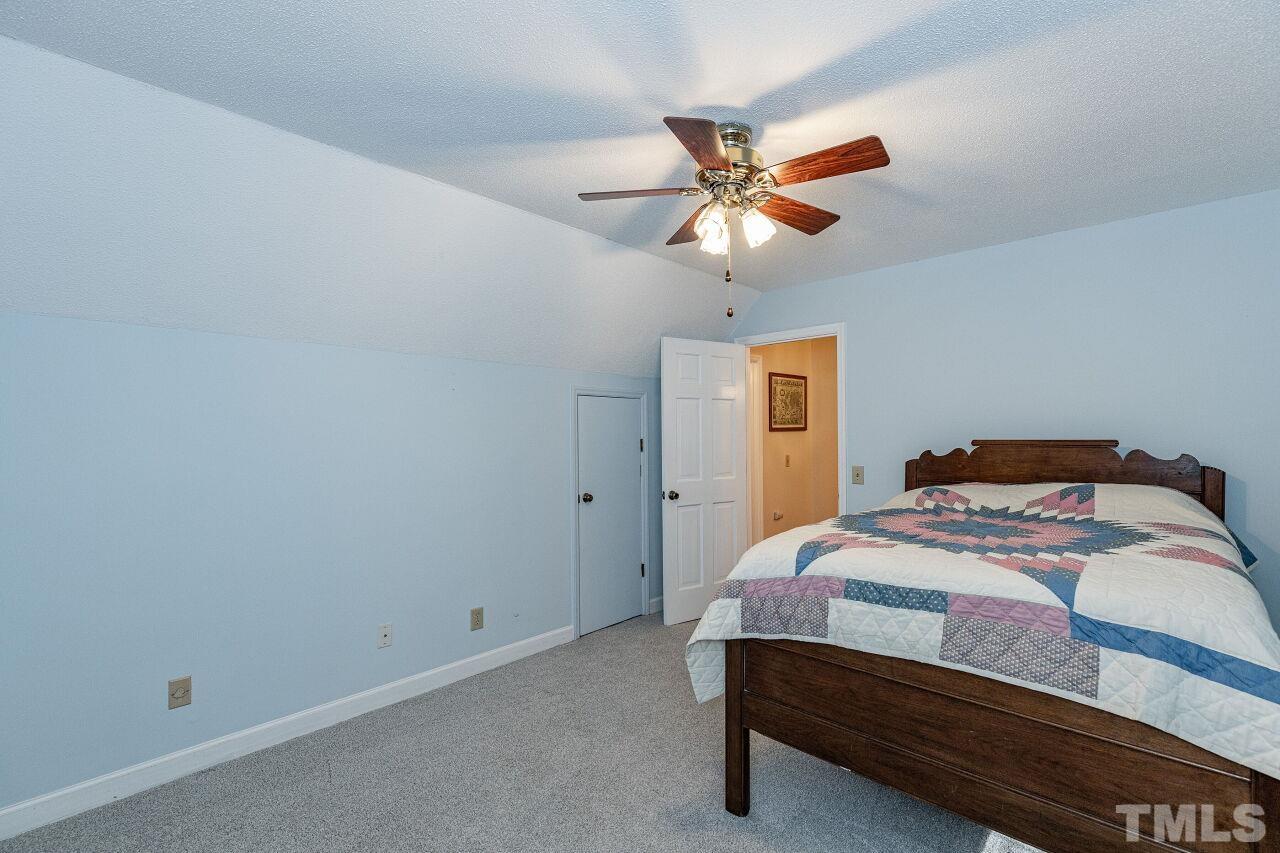 7811 Breckon Way Raleigh, NC 27615 - Photo 23 of 30 a bedroom with a bed and a chandelier