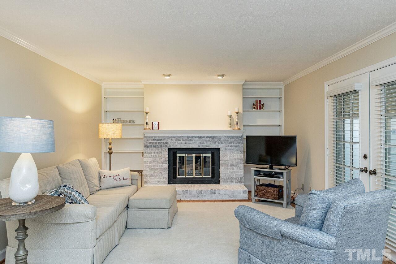 7811 Breckon Way Raleigh, NC 27615 - Photo 10 of 30 a living room with furniture a fireplace and a flat screen tv