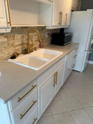 a utility room with stainless steel appliances a sink and cabinets