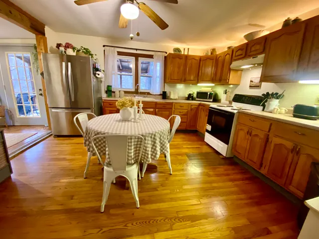 a living room with stainless steel appliances dining table flat screen tv and wooden floor