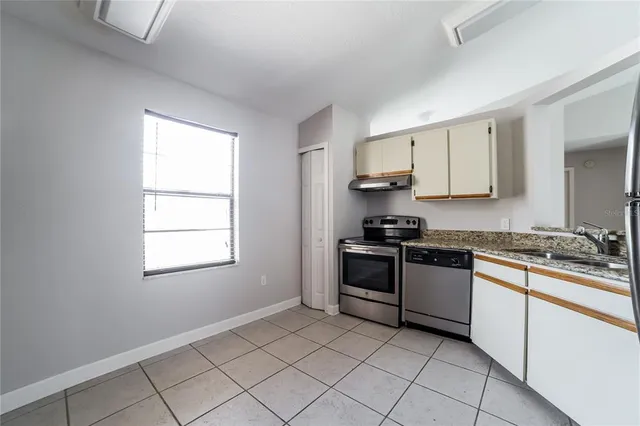 a kitchen with granite countertop white cabinets and appliances