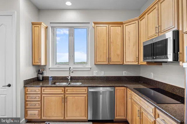 a kitchen with stainless steel appliances granite countertop a stove a sink a dining table and chairs with wooden floor