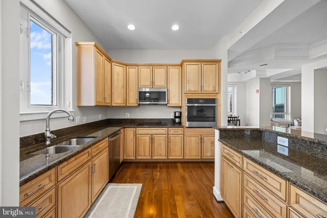 a kitchen with granite countertop stainless steel appliances a refrigerator cabinets and wooden floor