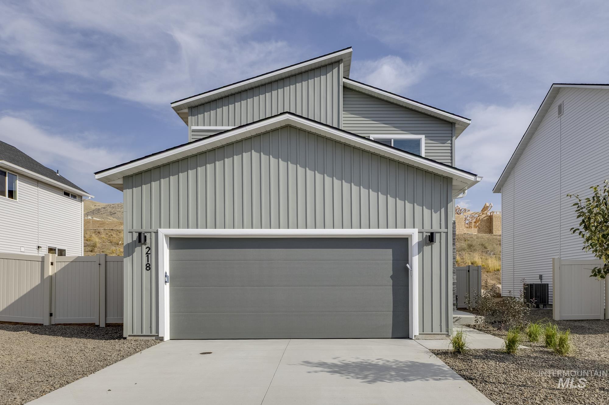 View of front of property featuring board and batten siding, a gate, and driveway