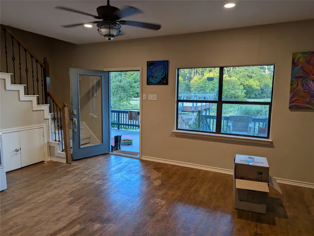 a view of an empty room with a window and wooden floor