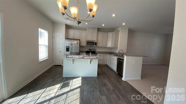 a kitchen with a microwave a stove a sink dishwasher a refrigerator and white cabinets with wooden floor