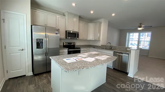 a kitchen with stainless steel appliances granite countertop a refrigerator a sink a stove a microwave and island