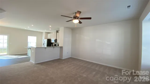 an empty room with kitchen view and a window