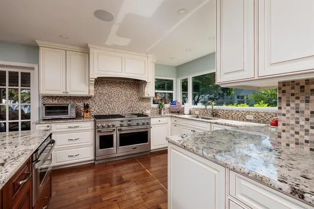 a kitchen with granite countertop a stove sink and cabinets