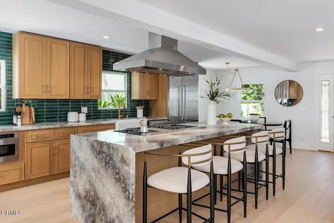 a kitchen with stainless steel appliances granite countertop a stove a sink dishwasher and chairs with wooden floor