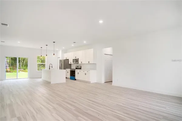 a view of a kitchen with kitchen island wooden floors appliances and a fireplace