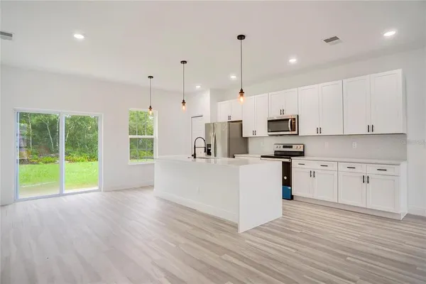a kitchen with stainless steel appliances kitchen island wooden floors and white cabinets