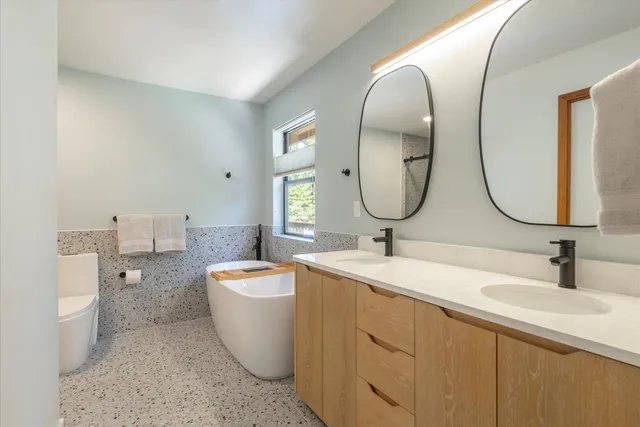 a bathroom with a double vanity sink mirror and bathtub