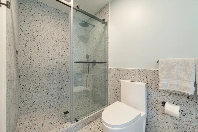 a white toilet sitting next to a bath tub and a shower