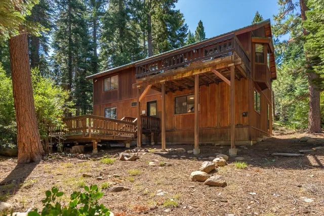 a backyard of a house with a large tree and wooden fence