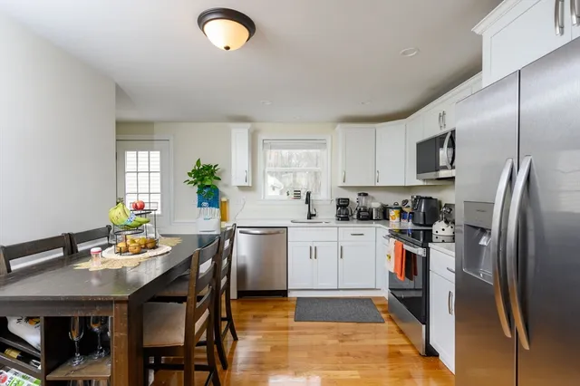 a kitchen with stainless steel appliances granite countertop a stove refrigerator a sink dishwasher a dining table and chairs with wooden floor