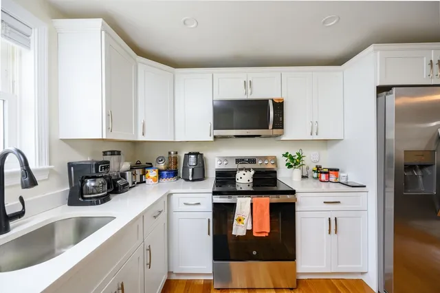 a kitchen with stainless steel appliances a sink a stove a refrigerator cabinets and a counter space