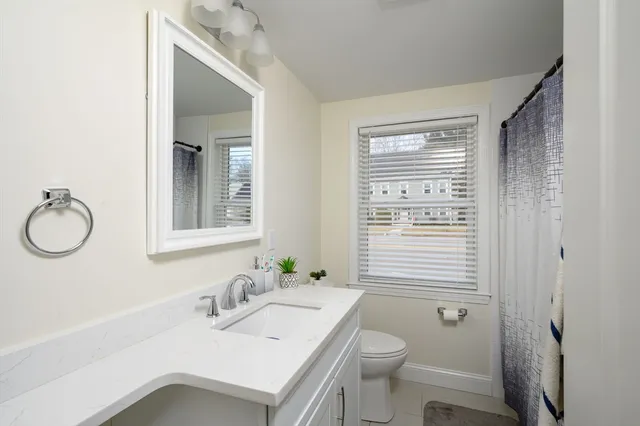 a bathroom with a granite countertop sink toilet and mirror
