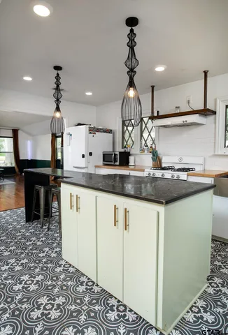 a kitchen with kitchen island granite countertop a sink cabinets and wooden floor