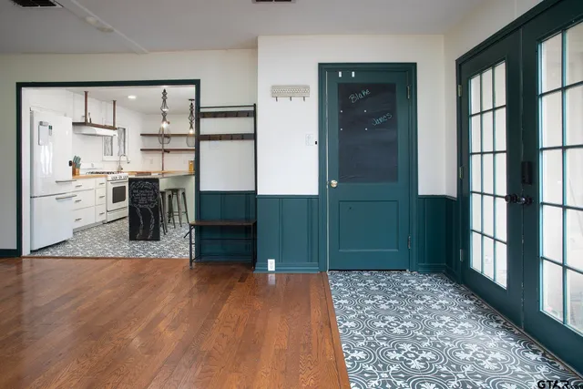 a living room with stainless steel appliances kitchen island granite countertop a refrigerator and a wooden floor