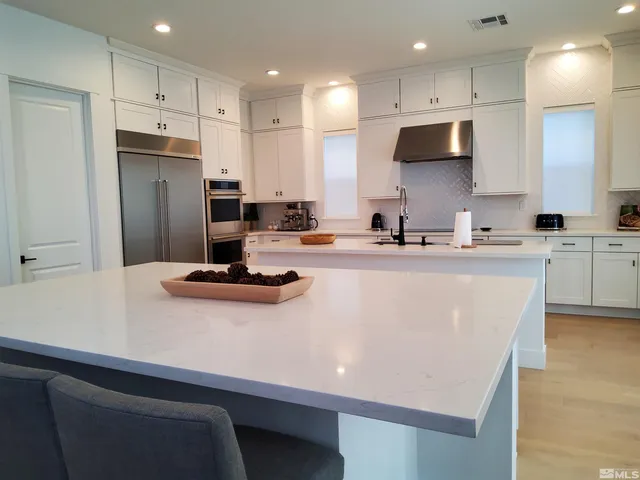 a kitchen with stainless steel appliances a sink a stove a refrigerator and cabinets