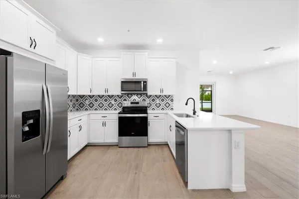 a kitchen with white cabinets and stainless steel appliances