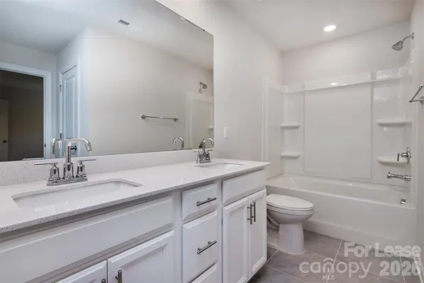 a bathroom with a granite countertop sink a toilet and bathtub