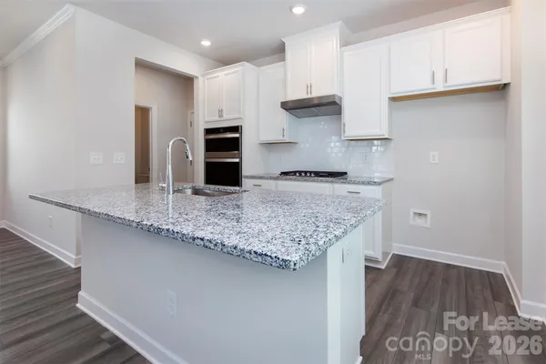 a kitchen with granite countertop a sink and refrigerator