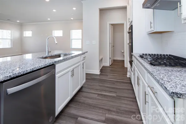 a large kitchen with granite countertop a sink and a wooden floor