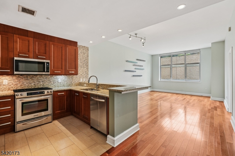 8100 River Road, Unit 210 North Bergen, NJ 07047 - Photo 9 of 25 a kitchen with stainless steel appliances granite countertop a stove a sink and a microwave