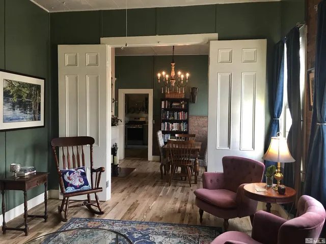 a living room with furniture a large window and wooden floor