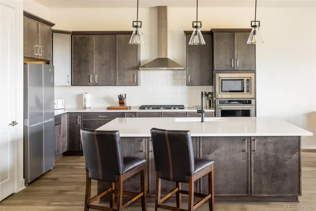 a kitchen with stainless steel appliances granite countertop a sink a stove a refrigerator and island with wooden floor