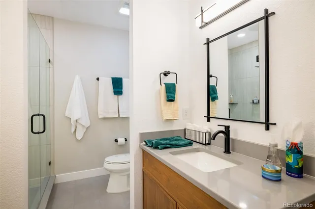 a bathroom with a granite countertop sink a toilet and shower