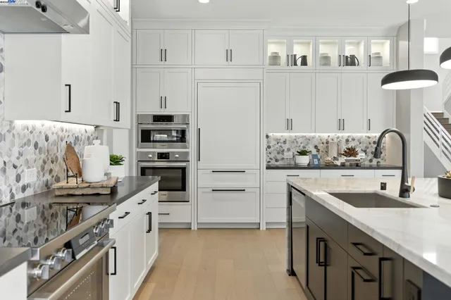a kitchen with stainless steel appliances kitchen island granite countertop a table chairs and white cabinets