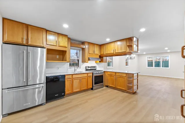 a kitchen with stainless steel appliances granite countertop a refrigerator a stove top oven and a sink