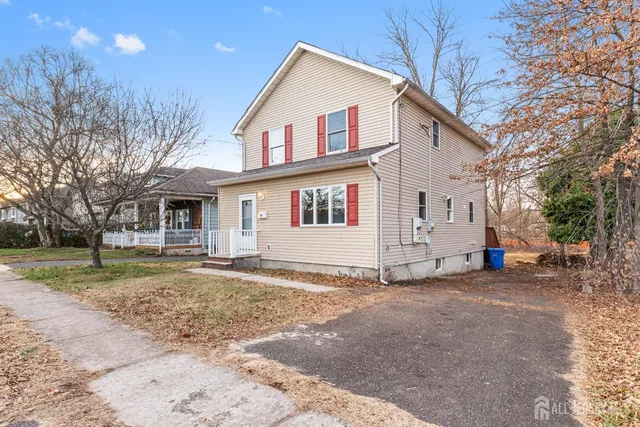 a view of a white house with a large tree in front of it