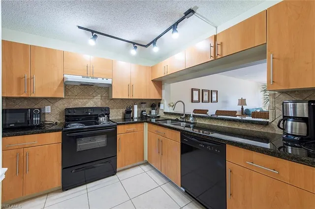 a kitchen with granite countertop a sink stainless steel appliances and cabinets