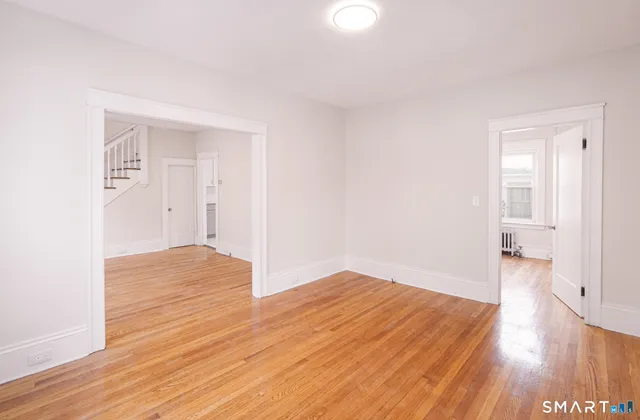 a view of an empty room with wooden floor and a window