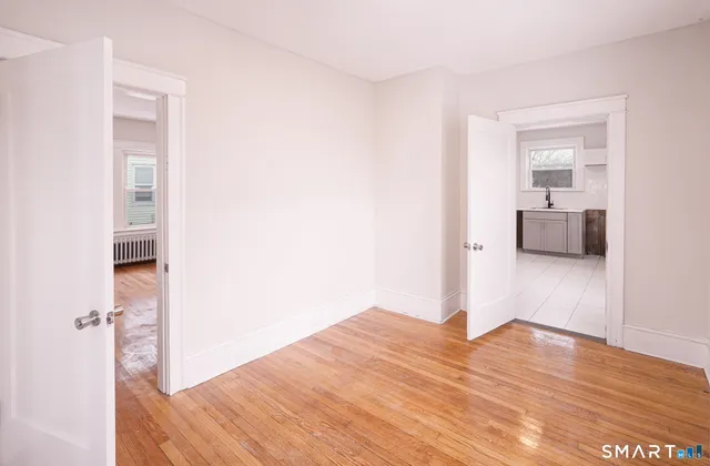 a view of an empty room with wooden floor and a window
