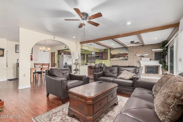 a living room with furniture a ceiling fan and a large window