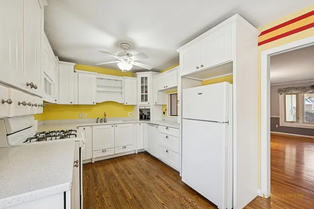a kitchen with a refrigerator a stove and white cabinets with wooden floor