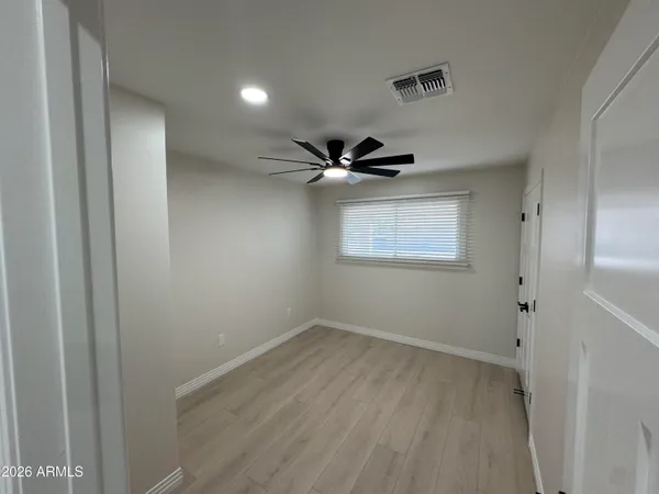 an empty room with wooden floor fan and windows