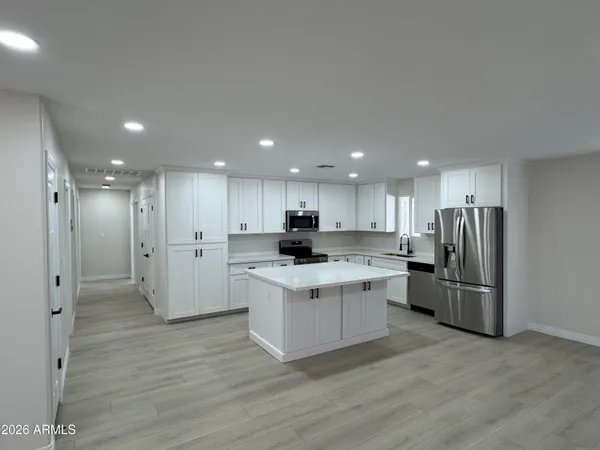 a kitchen with stainless steel appliances kitchen island granite countertop a refrigerator and a stove top oven